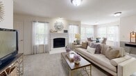 This single-floor residence offers a thoughtfully designed layout with a warm, neutral color palette throughout. The living room serves as a welcoming centerpiece, featuring a white-mantled fireplace, plush carpeting, and multiple windows dressed with sheer curtains and blinds that fill the space with natural light and outdoor views. The adjacent dining area continues the bright, airy feel with a glass-top dining table surrounded by upholstered chairs and additional windows overlooking greenery outside.

The kitchen is well-equipped with warm wood cabinetry, granite-style countertops, tile flooring, and a full suite of white appliances including a refrigerator with ice maker, electric range, and microwave. A peninsula provides additional counter space and casual seating.

The bedrooms are carpeted and comfortably sized, each featuring ceiling fans with light fixtures and ample closet space. One bedroom includes a walk-in closet, adding to the functional storage available throughout the home.

The bathrooms are finished with rich wood vanity cabinetry, light stone countertops, tile flooring, and well-lit vanity mirrors. One bathroom features a walk-in closet access, while the second includes a shower-tub combination. Together, the rooms create a cohesive, comfortable living environment with practical finishes and a welcoming ambiance.
