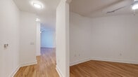 This single-floor residence offers a thoughtfully designed open-concept layout, seamlessly connecting the kitchen and living areas for a spacious, airy feel. The kitchen is a standout feature, showcasing white shaker cabinetry, a subway tile backsplash, stainless steel appliances, and a generously sized center island topped with granite countertops. Pendant lighting and recessed fixtures illuminate the space, while the adjacent living area benefits from a ceiling fan and access to natural light through a windowed door. The living and additional flex spaces feature warm hardwood-style flooring, complemented by crisp white walls and clean-lined trim throughout. Bedrooms are carpeted for comfort and each include ceiling fans and windows that invite natural light and outdoor views. The bathrooms are finished with granite-topped white vanities and brushed nickel hardware. The full bathroom features floor-to-ceiling tiled walls surrounding a soaking tub, while a second bathroom offers a clean, accessible layout with grab bars. The consistent use of light tones, quality finishes, and functional design details creates a cohesive, modern living environment throughout the entire residence.