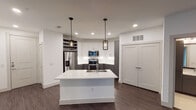 Located at 405 Crawford St in Fort Worth, TX, this single-floor residence offers a thoughtfully designed interior with modern finishes throughout. The open-concept kitchen serves as the centerpiece of the space, featuring a large white quartz island with an undermount sink, two-tone cabinetry with white upper and charcoal gray lower cabinets, a classic white subway tile backsplash, and a full suite of stainless steel appliances including a French door refrigerator, range, and microwave. Stylish pendant lights hang above the island, complementing the recessed lighting throughout. Dark hardwood-style flooring flows through the kitchen and living area, creating a warm, cohesive aesthetic. The spacious living area features a ceiling fan with integrated lighting and connects seamlessly to the rest of the unit. Bedrooms are finished with plush carpet and ceiling fans, each with natural light provided by blinded windows. The primary bathroom includes a wide vanity with a white countertop, dark cabinetry, a large framed mirror, and a glass-enclosed walk-in shower with subway tile surround. A secondary bathroom features a soaking tub with a curved rod and matching subway tile walls. The unit combines clean lines and contemporary design for a polished, move-in-ready feel.