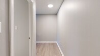Located at 3555 Austell Rd in Marietta, Georgia, this single-floor unit at building 3104 presents a clean, modern interior designed for comfortable everyday living. The open living area is finished with light-toned luxury vinyl plank flooring and neutral gray walls, creating a bright and welcoming atmosphere. Multiple windows fitted with blinds allow natural light to fill the space while offering views of the surrounding mature trees. The kitchen is a functional highlight, featuring white shaker-style cabinetry, granite countertops, a gray tile backsplash, and a full suite of stainless steel appliances including a gas range, built-in microwave, dishwasher, and refrigerator. A raised breakfast bar counter connects the kitchen to the main living area, ideal for casual dining or entertaining. The bedrooms are carpeted for comfort and include generous closet space — one bedroom notably features both a built-in shelving unit and a walk-in closet. The bathroom is finished with white tile surrounding a full soaking tub with chrome fixtures. Additional details include a textured ceiling throughout, recessed lighting, and a dedicated utility or storage room with vinyl plank flooring and a circular ceiling light. The property is set against a lush, wooded landscape that provides a tranquil natural setting.