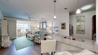 Located in Apopka, Florida, this single-story, 2-bedroom, 2-bathroom residence offers a thoughtfully designed open-concept floor plan that maximizes functionality and flow. The living, dining, and kitchen areas share a seamlessly connected space, anchored by durable wood-look plank flooring and bathed in natural light. The kitchen is a standout feature, boasting rich dark-wood cabinetry, gleaming granite countertops, stainless steel appliances, and a peninsula with pendant lighting that doubles as a casual dining or entertaining bar. Adjacent to the kitchen, the dining area accommodates a full table and is illuminated by a classic chandelier. The living room exudes a relaxed coastal ambiance, complete with a ceiling fan, a sliding barn door, and access to a bright sunroom or sitting area with large windows. Both bathrooms feature granite vanities and wood-toned cabinetry, with one including a full tub-shower combination. The spacious primary bedroom offers comfortable proportions, plush carpet, and direct access to its en-suite bathroom. Five closets throughout the home provide generous storage. A dedicated laundry area and multiple additional closets round out the practical amenities of this well-designed residence.