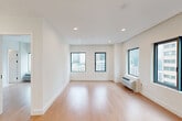 Located at 626 Summit Ave in Jersey City, NJ, this modern two-bedroom, two-bathroom residence offers a well-designed single-floor layout with a clean, contemporary aesthetic throughout. The open-concept kitchen is a standout feature, anchored by a large waterfall quartz island with an undermount sink and matte black faucet. Flat-panel sage-toned cabinetry reaches toward the ceiling, complemented by stainless steel appliances and a sculptural curved pendant light that adds an artistic touch. Light hardwood flooring flows throughout the living areas and both bedrooms, creating a warm, cohesive feel. Each bedroom is generously proportioned with crisp white walls, large black-framed windows that frame open city skyline views, and ample natural light. The primary bedroom includes a closet and direct access to a well-appointed en-suite bathroom featuring a glass-enclosed walk-in shower, a floating vanity with illuminated mirror, and floor-to-ceiling white tile. The second bathroom mirrors the same refined, all-white design with recessed lighting and modern black hardware accents. A connecting hallway ties the layout together efficiently, making the overall flow of the space feel intuitive and functional. The unit's modern finishes and elevated city views make it a polished urban residence.