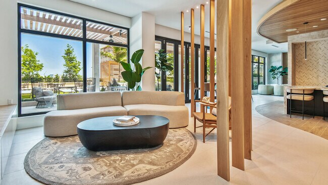 Salón para residentes de los apartamentos Griffis West Palm con lujoso sofá, mesa de café con libros y una decoración elegante. - Griffis West Palm