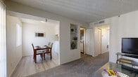 This efficiently designed single-floor residence accommodates three bedrooms and two bathrooms within a thoughtfully arranged floor plan. The carpeted living room serves as the central gathering space, featuring a sliding door with vertical blinds that allows natural light to filter in. Built-in wall shelving adds a decorative touch and connects the living area to the rest of the unit. Adjacent to the living room, the dining area offers light hardwood-style flooring and a window with vertical blinds, creating a bright setting for meals. The compact kitchen is equipped with standard appliances including a stove and full-size refrigerator, complemented by cabinetry and countertops in neutral tones. The primary bedroom features plush carpet, a window for natural light, and a textured ceiling, providing a comfortable retreat. Additional bedrooms offer similar finishes with carpet flooring. Both bathrooms are clean and functional, each featuring a full tub-shower combination with modern fixtures and light hardwood-style flooring. A hallway with bi-fold closet doors provides practical storage. Throughout the residence, a consistent neutral color palette, textured ceilings, and ceiling vents contribute to a cohesive, well-maintained interior ambiance.