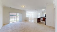 This single-floor residence is designed with an open-concept layout that seamlessly connects the living, dining, and kitchen areas into one expansive, light-filled space. Large windows and a sliding glass door leading to a private balcony flood the main living area with natural light, offering views of the surrounding exterior. Soft, neutral carpeting covers the generous living space, complementing the bright white walls throughout.

The kitchen is a standout feature, equipped with rich dark-cherry cabinetry extending to the upper walls, granite countertops, and a full suite of stainless steel appliances including a refrigerator, range, microwave, and dishwasher. A large kitchen island with a granite surface provides additional workspace and serves as a natural divider between the kitchen and living areas. Wood-look flooring runs throughout the kitchen, adding warmth and contrast.

The bedrooms are carpeted and well-lit by windows with outdoor views, offering comfortable, quiet retreats. The bathrooms mirror the kitchen's finishes, featuring dark cabinetry, granite countertops, and large mirrors, maintaining a cohesive design aesthetic throughout the unit.