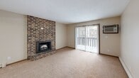 Located at 2250 S 34th St in Grand Forks, North Dakota, this 2-bedroom, 1-bathroom unit offers a practical and comfortable single-floor layout. The combined kitchen and living area forms the heart of the home. The galley-style kitchen is well-equipped with rich, dark wood cabinetry extending to the ceiling for ample storage, white appliances including a range, refrigerator, and microwave, a double-basin sink, and light-toned countertops over durable tile flooring. The living room is a standout space, anchored by a full-height brick fireplace that adds warmth and character. A sliding glass door floods the room with natural light and provides outdoor access, while a wall-mounted AC unit ensures year-round comfort. Soft carpet underfoot extends throughout the living and bedroom areas. The primary bedroom is generously proportioned, featuring a ceiling fan, a window with vertical blinds, and a baseboard heating unit. The second bedroom also offers carpeted floors, natural light, and a wide bi-fold closet. The full bathroom includes a combined tub and shower with a clean, white surround and tile flooring. Multiple hallways connect the rooms efficiently throughout the layout, with textured ceilings present throughout the unit.