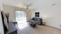 This well-appointed 2-bedroom, 2-bathroom residence is thoughtfully laid out across a single floor, offering a functional and comfortable living experience. The living room serves as the heart of the home, featuring plush wall-to-wall carpeting, neutral wall tones, and a ceiling fan that contributes to a bright and airy atmosphere. A large sliding glass door floods the space with abundant natural light and provides direct access to an outdoor area, where views of the surrounding greenery can be enjoyed. The living area comfortably accommodates a full seating arrangement, making it well-suited for both relaxing and entertaining. The neutral color palette throughout creates a clean, versatile backdrop that adapts easily to a variety of décor styles. With two bedrooms and two full bathrooms, the layout offers both privacy and practicality, making it an excellent option for roommates, guests, or those who need dedicated space for a home office. The overall design emphasizes ease of living with a cohesive, understated aesthetic that feels both welcoming and move-in ready.