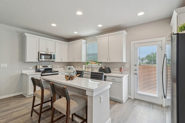 Amplia cocina con isla y electrodomésticos de acero inoxidable. - Solstice Springs