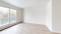 This well-appointed 2-bedroom, 1-bathroom unit is located at 109-123 Westwood Dr in Kitchener, Ontario. The interior is finished with light-toned laminate flooring throughout, crisp white walls, and clean white trim, creating a bright and cohesive aesthetic across every room. The open living area is generously sized, offering a welcoming space filled with natural light from large windows and a sliding door that leads to a balcony overlooking the surrounding grounds and treed landscape. The galley-style kitchen is efficiently designed, featuring white shaker cabinetry, dark countertops, subway tile backsplash, a stainless steel sink, and stainless steel appliances including a refrigerator, electric range, microwave, and dishwasher. The spacious primary bedroom accommodates generous furnishings and includes a window with outdoor views, while the second bedroom is well-proportioned and similarly finished with closet access. The full bathroom is outfitted with a soaker tub and shower combination surrounded by classic white subway tile. Baseboard heating is present throughout the unit. The hallway connects all rooms efficiently, completing the practical and clean layout of this move-in ready residence.