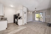 This single-floor residence offers a thoughtfully designed layout across two bedrooms, one bathroom, and a well-equipped kitchen. The galley-style kitchen is a standout feature, finished with white shaker cabinetry, granite-look countertops, and black appliances including a refrigerator, range, and built-in microwave. Light wood-style flooring runs through the kitchen, which also benefits from abundant cabinet storage extending to the ceiling. A convenient in-unit stacked washer and dryer is tucked behind louvered doors adjacent to the kitchen.

The open living area is carpeted and bathed in natural light from a sliding glass door that leads to an outdoor space. A ceiling fan with integrated lighting provides comfort and airflow. Both bedrooms are carpeted and feature ceiling fans, natural light from windows with blinds, and neutral wall tones. The primary bedroom includes mirrored closet doors and overhead cabinetry for added storage.

The bathroom is finished with a granite-topped white vanity, wood-look tile flooring, and a shower-tub combination. Throughout the residence, a consistent neutral palette and clean finishes create a bright, cohesive ambiance.