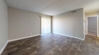 Located at Quails Lake Village in Norcross, GA, this single-floor, 2-bedroom, 1-bathroom unit offers a practical and comfortable layout across a modest footprint. The living room features dark wood-look vinyl flooring and a sliding glass door that welcomes natural light, creating an open and airy feel. Neutral gray walls and textured ceilings are consistent throughout, lending the space a clean, uniform aesthetic.

The galley-style kitchen is efficiently designed with white cabinetry, light countertops, and stainless steel appliances including a refrigerator, range, and dishwasher. Wood-look flooring continues through this area, maintaining visual continuity with the living space.

Both bedrooms are carpeted in warm beige tones and feature neutral walls with white trim. The primary bedroom includes a double-door closet, providing ample storage. The second bedroom also offers comfortable dimensions and access to a dedicated closet area. Each room is served by natural light through window blinds.

The bathroom is equipped with a full-size soaking tub and shower combination with a white surround and built-in shelving niches. Clean, white fixtures complete the functional design. Overall, the unit presents a straightforward, well-maintained layout suited for everyday living.