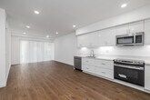 Located at 1011 Everett St in the Echo Park neighborhood of Los Angeles, this 1-bedroom, 1-bathroom unit offers a clean, modern aesthetic with thoughtful design throughout. The open-concept kitchen and living area forms the heart of the space, featuring warm wood-look flooring that extends throughout the unit, crisp white walls, and recessed lighting. The kitchen is outfitted with sleek white flat-panel cabinetry, stainless steel appliances including a refrigerator, dishwasher, range with oven, and microwave, as well as a single-basin sink — all arranged along a functional L-shaped layout. The living area benefits from a large sliding door with vertical blinds, allowing generous natural light to fill the room. The bedroom is a well-proportioned private retreat with a window overlooking the exterior, fitted with blinds, and the same consistent flooring and bright white walls. The bathroom is finished with a floating dark-toned vanity with a white countertop, a full soaking tub, and a marble-patterned tile surround that adds an elevated touch. Additional features include a dedicated closet, in-unit laundry, and an electrical panel. The unit presents a bright, move-in-ready living environment with a cohesive modern design.