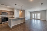 Located at 16000 Rushmore Avenue in Little Rock, AR, this well-appointed single-story home offers four bedrooms and two full bathrooms within a thoughtfully designed open floor plan. Rich hardwood-style flooring flows consistently throughout the entire home, creating a cohesive and warm aesthetic.

The open-concept kitchen and living area serves as the heart of the home. The kitchen is equipped with taupe shaker-style cabinetry, granite countertops, a full suite of stainless steel appliances, and a peninsula island with a built-in sink accented by stylish pendant lighting overhead. The adjacent living room is generously proportioned, featuring neutral walls and French doors that open to an outdoor balcony, flooding the space with natural light.

The four bedrooms are well-sized, with the primary bedroom offering ample floor space. Each room features the same durable hardwood-style flooring, neutral paint, and windows that invite natural light. Both bathrooms mirror the home's consistent design language, showcasing granite-topped vanities with taupe cabinetry and full tub-shower combinations. The clean, modern finishes throughout reflect a move-in-ready condition, making this home a practical and attractive option in the Little Rock area.