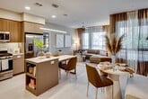 Located at 1912 S Jacaranda St in Anaheim, California, this thoughtfully designed single-floor residence offers a seamless blend of modern aesthetics and functional living. The open-concept layout connects the kitchen, dining, and living areas into a cohesive, light-filled space. Large windows dressed with sheer and layered draping allow natural light to pour in throughout, creating a warm, inviting ambiance.

The kitchen is outfitted with stainless steel appliances — including a gas range, built-in microwave, and French door refrigerator — complemented by a two-tone cabinetry design featuring warm wood uppers and taupe lowers, white quartz countertops, and a central island with seating. The adjacent dining and living areas flow naturally, anchored by light hardwood-style flooring and ceiling fans.

Both bedrooms are generously proportioned and bathed in natural light, with large windows and soft neutral tones. The primary bedroom features a walk-in closet, while both bathrooms showcase floating wood-grain vanities, white quartz countertops, full-wall tile surrounds, and soaking tub-shower combinations. The primary bath includes a dual-sink vanity with a wide illuminated mirror. The overall design palette of warm taupes, soft grays, and natural wood tones lends a cohesive, contemporary feel throughout.