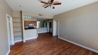 This single-floor residence offers a well-designed, open-concept layout that seamlessly connects the living area to the kitchen. Rich hardwood-style flooring runs throughout the main living spaces, complemented by warm neutral-toned walls and crisp white baseboards that create a clean, cohesive aesthetic. Ceiling fans are present throughout, contributing to both comfort and airflow.

The kitchen is efficiently laid out and features warm-toned wood cabinetry, dark granite countertops, and black appliances including a refrigerator, range, and built-in microwave. A peninsula counter provides an informal dining or prep area while maintaining the open flow of the space.

The living area is spacious and bright, with a sliding glass door that opens to a private balcony, allowing natural light to pour in and offering outdoor views. Additional rooms include a carpeted bedroom with a built-in closet and a window with natural light, as well as a secondary room with its own sliding glass door access to the balcony.

The bathrooms are appointed with dark granite vanity tops, warm wood cabinetry, and well-lit mirrors. One bathroom includes a full tub-shower combination. A washer and dryer unit is also present within the space, adding everyday convenience. Overall, the residence presents a functional and cohesive living environment.