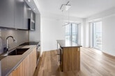 Located at 151 Mill St in Toronto's vibrant St. Lawrence neighbourhood, this thoughtfully designed three-bedroom, two-bathroom unit offers a bright and functional layout across a single floor. Light hardwood flooring runs throughout the living areas and bedrooms, complementing the clean white walls and modern aesthetic.

The open-concept kitchen and dining area is a standout feature, showcasing two-tone cabinetry with warm wood lower cabinets and sleek grey uppers, stainless steel appliances, a subway tile backsplash, and a kitchen island with additional storage — ideal for both everyday living and entertaining.

The primary bedroom benefits from floor-to-ceiling windows that frame expansive city views, while additional bedrooms are well-proportioned and include closet storage with sliding doors. The hallway conveniently houses a stacked in-unit washer and dryer.

Two well-appointed bathrooms serve the unit: one features a glass-enclosed walk-in shower with large-format tile and wood-accented vanity, while the second includes a soaking tub surrounded by elegant stone-look tile. Recessed lighting and a neutral colour palette throughout create a cohesive, contemporary atmosphere ideal for urban living.