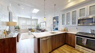 Located at 255 N 400 W in Salt Lake City, Utah, this well-designed two-bedroom, two-bathroom residence offers a thoughtfully organized single-floor layout. The open-concept living and kitchen area serves as the heart of the home, bathed in natural light from large windows and accented by a skylight overhead. A ceiling fan adds comfort to the bright living room, which features wood-look flooring throughout.

The kitchen is a standout, showcasing warm walnut-toned cabinetry, a quartz waterfall-edge peninsula with seating for three, subway tile backsplash, stainless steel appliances, and stylish pendant lighting. Frosted-glass upper cabinets add a modern touch.

The spacious primary bedroom offers a serene retreat with carpeted flooring, a large window, and access to a generous walk-in closet outfitted with built-in shelving and dual hanging rods. Its en-suite bathroom features a walk-in glass shower with subway tile, a wood-toned vanity with quartz countertop, and wood-look tile flooring. The second bathroom mirrors the same refined aesthetic with a shower/tub combination.

The second bedroom is well-proportioned with neutral tones and natural light. A connecting hallway ties all spaces together seamlessly, creating a cohesive and functional floor plan throughout.