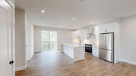 Located at 7 W Parker Ave in Maplewood, NJ, this thoughtfully designed 2-bedroom, 2-bathroom residence offers a clean, modern aesthetic with high-quality finishes throughout. The open-concept living and kitchen area serves as the heart of the home, anchored by a stunning waterfall-edge quartz island. The kitchen is outfitted with crisp white shaker cabinets, a tile backsplash, stainless steel appliances including a range and refrigerator, a wall-mounted range hood, and recessed lighting — all set atop warm hardwood-style flooring that flows seamlessly through the entire unit. A sliding glass door opens to a private balcony with greenery views, filling the living space with abundant natural light. A well-proportioned hallway connects the bedrooms and bathrooms, maintaining a clean, organized layout. The primary bedroom features a private balcony access with leafy outdoor views. The second bedroom offers two large windows framing treetop scenery, creating a bright and airy feel. Both bedrooms include closet space. The two bathrooms feature large-format tile, modern vanities, and matte black fixtures — one with a soaking tub and the other with a glass-enclosed walk-in shower.