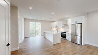 Located at 7 W Parker Ave in Maplewood, NJ, this thoughtfully designed 2-bedroom, 2-bathroom residence offers a clean, modern aesthetic with high-quality finishes throughout. The open-concept living and kitchen area serves as the heart of the home, anchored by a stunning waterfall-edge quartz island. The kitchen is outfitted with crisp white shaker cabinets, a tile backsplash, stainless steel appliances including a range and refrigerator, a wall-mounted range hood, and recessed lighting — all set atop warm hardwood-style flooring that flows seamlessly through the entire unit. A sliding glass door opens to a private balcony with greenery views, filling the living space with abundant natural light. A well-proportioned hallway connects the bedrooms and bathrooms, maintaining a clean, organized layout. The primary bedroom features a private balcony access with leafy outdoor views. The second bedroom offers two large windows framing treetop scenery, creating a bright and airy feel. Both bedrooms include closet space. The two bathrooms feature large-format tile, modern vanities, and matte black fixtures — one with a soaking tub and the other with a glass-enclosed walk-in shower.