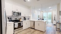 This thoughtfully designed 1-bedroom, 1-bathroom unit offers a functional and modern open-concept layout across a single floor. Light wood-style flooring flows seamlessly throughout the space, creating a cohesive and contemporary aesthetic.

The kitchen is a standout feature, outfitted with crisp white cabinetry, a marble-style tile backsplash, white quartz countertops, and a full suite of stainless steel appliances including an electric range, over-the-range microwave, dishwasher, and refrigerator. Pendant lighting over the peninsula adds a polished finishing touch, while the open layout connects the kitchen directly to the living area.

The living room is bright and airy, benefiting from large floor-to-ceiling windows and a sliding glass door that fills the space with natural light and offers outdoor views. A ceiling fan adds comfort to the space.

The bedroom is a cozy and well-lit retreat, featuring large windows with horizontal blinds that allow for natural light while maintaining privacy. The bathroom maintains the clean, modern aesthetic of the rest of the unit, with white cabinetry, a white vanity countertop, and wood-style flooring. Additional storage is provided by multiple closets near the entryway, maximizing the efficiency of the layout.