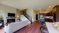 This well-designed two-story home offers a thoughtful layout that balances open living spaces with comfortable private retreats. The main floor showcases an open-concept design where the living, dining, and kitchen areas flow seamlessly together, all finished with rich hardwood flooring. The living room centers around a fireplace and features recessed lighting, while a staircase with sleek metal balusters leads to the upper level. The gourmet kitchen is a standout, boasting rich dark wood cabinetry, a classic white subway tile backsplash, light quartz countertops, stainless steel appliances, and a central island with seating — ideal for both cooking and casual dining. A conveniently located half bathroom on the main floor features matching hardwood flooring and dark cabinetry. Upstairs, the bedrooms are bright and inviting, each with large windows that draw in natural light and offer views of the surrounding neighborhood. The primary bedroom provides a serene retreat with a ceiling fan and generous proportions. A full bathroom serves the upper level, complete with a soaking tub and shower combination and clean, neutral finishes throughout. The overall aesthetic is modern and cohesive, combining warm wood tones with neutral walls for a welcoming ambiance.