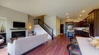 This well-designed two-story home offers a thoughtful layout that balances open living spaces with comfortable private retreats. The main floor showcases an open-concept design where the living, dining, and kitchen areas flow seamlessly together, all finished with rich hardwood flooring. The living room centers around a fireplace and features recessed lighting, while a staircase with sleek metal balusters leads to the upper level. The gourmet kitchen is a standout, boasting rich dark wood cabinetry, a classic white subway tile backsplash, light quartz countertops, stainless steel appliances, and a central island with seating — ideal for both cooking and casual dining. A conveniently located half bathroom on the main floor features matching hardwood flooring and dark cabinetry. Upstairs, the bedrooms are bright and inviting, each with large windows that draw in natural light and offer views of the surrounding neighborhood. The primary bedroom provides a serene retreat with a ceiling fan and generous proportions. A full bathroom serves the upper level, complete with a soaking tub and shower combination and clean, neutral finishes throughout. The overall aesthetic is modern and cohesive, combining warm wood tones with neutral walls for a welcoming ambiance.