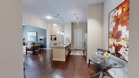 This single-floor residence offers a thoughtfully designed layout encompassing two bedrooms, two bathrooms, a kitchen, living room, two closets, and an in-unit laundry area. Rich hardwood flooring flows throughout the main living areas, complementing the open-concept design that connects the kitchen, dining, and living spaces seamlessly.

The kitchen features dark espresso cabinetry, granite countertops, stainless steel appliances including a French door refrigerator, and a center island with seating — ideal for both everyday cooking and entertaining. Pendant lighting adds a modern touch overhead.

The living room is highlighted by soaring ceilings, a ceiling fan, and large French doors that invite abundant natural light and outdoor views. A bold accent wall and hardwood floors enhance the contemporary aesthetic.

The primary bedroom offers plush carpeting, a spacious walk-in closet with wire shelving, and generous natural light. The second bedroom similarly features carpet and a bright window. Both bathrooms include dark vanity cabinetry with white countertops and tub-shower combinations.

The dedicated laundry area houses a full-size washer and dryer with overhead shelving for added storage, completing this well-equipped and stylish residence.
