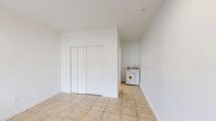 This efficiently designed 220 square foot studio apartment in Hialeah, Florida, offers a practical living solution in a single-floor layout. The space comprises a 180 square foot primary bedroom area and a full bathroom, making the most of its compact footprint. Throughout the apartment, neutral-toned ceramic tile flooring creates a sense of continuity and easy maintenance.

The main living area is bathed in natural light from a large window, complemented by recessed lighting for evening ambiance. A wall-mounted air conditioning unit provides climate control, essential for Florida's warm climate. The room's clean, white walls offer a blank canvas for personalization.

The bathroom features modern fixtures, including a full-sized bathtub with shower, a sleek vanity with storage, and a standard toilet. A window in the bathroom allows for natural ventilation. The bedroom area, while open to the main space, can be partially separated for privacy, likely through the use of curtains or room dividers.

Storage is cleverly integrated, with a closet featuring sliding doors to maximize space efficiency. The apartment's minimalist design and neutral color palette create a sense of openness, making the compact space feel larger and providing residents with a versatile canvas for their personal style.