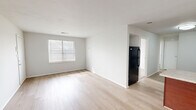 Located at 5313 Justin Ct in Virginia Beach, VA, this two-bedroom, one-bathroom single-floor residence offers a practical and clean layout designed for comfortable everyday living. The open-concept kitchen and living area serves as the heart of the home, featuring light hardwood-style flooring that runs throughout the shared spaces, crisp white walls, and natural light streaming in through slatted blinds. The kitchen is well-appointed with rich dark wood cabinetry, granite-look countertops, a double-basin sink, and a full suite of black appliances including a refrigerator, dishwasher, and range. A peninsula provides added prep space and visually connects the kitchen to the living area. Both bedrooms are carpeted, offering a warm and quiet feel, and each includes a window for natural light and access to closet storage. The two dedicated closets provide practical storage throughout the unit. The bathroom features a full soaking tub with clean white subway tile surround, maintaining the home's consistent, neutral aesthetic. Overall, the space presents a bright, move-in-ready environment with a cohesive design throughout.
