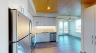 Located at 1090 NE 91st Ave in Hillsboro, Oregon, this thoughtfully designed single-floor residence blends modern finishes with warm architectural details throughout. A standout feature of the space is the natural wood-paneled ceiling that spans the kitchen and living areas, adding warmth and texture to the otherwise clean, contemporary aesthetic.

The kitchen is well-appointed with white flat-front cabinetry, light countertops, a white subway tile backsplash with under-cabinet lighting, and a full suite of stainless steel appliances including a range, over-the-range microwave, dishwasher, and refrigerator. Wood-toned luxury vinyl plank flooring ties the kitchen seamlessly into the open living area, which is brightened by large windows and French doors that open onto a private balcony offering views of the surrounding neighborhood.

The bedrooms feature plush carpeting, ceiling fans, natural wood ceilings, and generous windows that invite abundant natural light. The bathrooms are clean and functional — one featuring a undermount sink with light quartz countertops and a tub-shower combination, while the second offers built-in shelving, wood-look flooring, and a shower-tub combo. Ceiling fans throughout the unit enhance comfort and airflow. The overall ambiance is bright, modern, and welcoming.