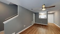 Located at 480 Murray Rd in Valdosta, Georgia, this two-story home offers a well-organized layout across two levels, combining functional design with modern finishes throughout. The main level features a generous open living area dressed in warm wood-look vinyl plank flooring and cool gray-painted walls with crisp white trim. A ceiling fan provides comfort overhead, while a pass-through window connects the living space directly to the kitchen, enhancing the open feel. The kitchen is equipped with white shaker-style cabinetry, light stone countertops, a decorative tile backsplash, and black appliances including a refrigerator, electric range, built-in microwave, and dishwasher. A dedicated laundry area with a stacked washer and dryer unit adds everyday convenience. The bathroom features a full tub-shower combination with clean white surrounds, a vanity with countertop sink, and wood-look flooring. Upstairs, carpeted bedrooms offer a quieter, comfortable retreat, each painted in the same soft gray palette with natural light from windows. The staircase connects both floors seamlessly, with a landing area that provides additional utility space. Overall, the home presents a clean, updated aesthetic suitable for comfortable everyday living.