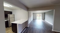 Located at 2006 W Algonquin Rd in Mount Prospect, Illinois, this single-floor unit offers a thoughtfully updated interior with a cohesive modern aesthetic throughout. The open living area is a standout feature, showcasing dark hardwood-style flooring, neutral gray walls, and a sliding glass door that invites natural light and provides direct views of the surrounding greenery. The layout flows seamlessly from the living space into the kitchen, which is defined by dark espresso cabinetry, light quartz-style countertops, a mosaic tile backsplash, and a full suite of stainless steel appliances including a refrigerator, range, and dishwasher. A breakfast bar provides additional counter space and casual dining options.

The bedrooms are carpeted for comfort and feature neutral tones and windows with vertical blinds that allow for natural light. The primary bedroom includes dual closets with built-in shelving, offering generous storage capacity. The bathroom is well-appointed with a dark vanity featuring a granite-style countertop, a full tub-and-shower combination with a clean white surround, and earth-toned tile flooring. Overall, the unit presents a clean, updated interior suitable for comfortable everyday living.