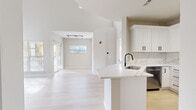 Located at 507 Chamberlain Lane in Naperville, Illinois, this two-story home presents a clean, modern aesthetic defined by neutral tones, quality finishes, and an abundance of natural light. The main level features an open-concept layout where the living area flows seamlessly into the kitchen and dining space. Soaring vaulted ceilings amplify the sense of openness, while large windows invite generous sunlight across the light-toned hardwood-style flooring.

The kitchen serves as a centerpiece of the main floor, showcasing white shaker cabinetry with matte black hardware, a striking marble-look quartz countertop and backsplash, and a waterfall peninsula with an undermount sink. Stainless steel appliances, including a refrigerator, range, over-the-range microwave, and dishwasher, complete the space with a polished, functional appeal. Track lighting overhead adds focused illumination.

The bedrooms are finished with plush carpeting and receive ample natural light through blinded windows, offering a comfortable, quiet retreat. Bathrooms are well-appointed with white vanity cabinetry, stone-look countertops, tiled tub-shower combinations, and warm neutral tile flooring. Matte black hardware details appear consistently throughout, providing a cohesive modern touch across the entire home.