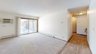 Located in Eagan, Minnesota, this two-bedroom, three-bathroom residence offers a well-organized single-floor layout designed for comfortable everyday living. The galley-style kitchen features warm oak cabinetry, granite-look countertops, a double-basin sink, a dishwasher, and an electric range — all set atop durable hardwood-style flooring that extends into the adjoining living and dining areas. The open living space is bright and inviting, highlighted by a ceiling fan, a textured ceiling, and a sliding glass door that fills the room with natural light and provides access to an outdoor balcony. Neutral carpet covers the bedroom areas, creating a cozy contrast to the hard-surface flooring elsewhere. The spacious primary bedroom comfortably accommodates large furniture and includes its own dedicated bathroom. The second bedroom also offers generous proportions, a large window with outdoor views, and easy access to a well-appointed bath featuring a tiled tub/shower combination with safety grab bars. Four closets throughout the unit ensure abundant storage. Each bathroom includes a vanity with cabinet storage. The overall palette of soft neutrals, wood-toned trim, and consistent finishes gives the home a cohesive, move-in-ready appeal.