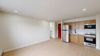 Located at 921 Tyson Ave in Philadelphia's Fox Chase neighborhood, this efficiently designed one-bedroom, one-bathroom unit offers a clean, modern aesthetic throughout. Light-toned hardwood flooring runs continuously across the entire space, contributing to a bright and cohesive feel.

The open-plan kitchen and living area form the heart of the unit. The kitchen is equipped with warm wood cabinetry, a stainless steel refrigerator, gas range, built-in microwave, and a white subway tile backsplash. A bold red entry door adds a distinctive architectural accent to the living area.

The bedroom is a well-proportioned private retreat featuring a double-door closet for ample storage, a large window that brings in natural light with neighborhood views, and baseboard heating. An additional wall-unit air conditioner is present in the secondary room area, ensuring year-round comfort. Two closets serve the unit overall, offering practical storage solutions.

The bathroom is finished in a contemporary style, featuring large-format light tile surrounding a soaking tub with an overhead shower, matte black fixtures, a wood vanity with a white sink basin, and a frameless mirror — all contributing to a clean, modern look.

Recessed lighting throughout and crisp white walls keep the space feeling open and airy, making this a well-appointed unit ideal for comfortable city living.