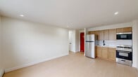 Located at 921 Tyson Ave in Philadelphia's Fox Chase neighborhood, this efficiently designed one-bedroom, one-bathroom unit offers a clean, modern aesthetic throughout. Light-toned hardwood flooring runs continuously across the entire space, contributing to a bright and cohesive feel.

The open-plan kitchen and living area form the heart of the unit. The kitchen is equipped with warm wood cabinetry, a stainless steel refrigerator, gas range, built-in microwave, and a white subway tile backsplash. A bold red entry door adds a distinctive architectural accent to the living area.

The bedroom is a well-proportioned private retreat featuring a double-door closet for ample storage, a large window that brings in natural light with neighborhood views, and baseboard heating. An additional wall-unit air conditioner is present in the secondary room area, ensuring year-round comfort. Two closets serve the unit overall, offering practical storage solutions.

The bathroom is finished in a contemporary style, featuring large-format light tile surrounding a soaking tub with an overhead shower, matte black fixtures, a wood vanity with a white sink basin, and a frameless mirror — all contributing to a clean, modern look.

Recessed lighting throughout and crisp white walls keep the space feeling open and airy, making this a well-appointed unit ideal for comfortable city living.
