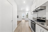 Located on W Martin Luther King Jr Blvd in Los Angeles, CA, this efficiently designed one-bedroom, one-bathroom unit offers a clean, modern aesthetic throughout its single floor. Light wood-style luxury vinyl flooring runs continuously across all rooms, creating a cohesive and contemporary feel.

The kitchen is well-appointed with white shaker-style cabinetry, taupe quartz countertops, and stainless steel appliances including an electric range and refrigerator. An under-cabinet range hood and a single-basin sink round out the functional workspace, making the most of the galley-style layout.

The bedroom is bright and airy, benefiting from a tall vertical window that brings in natural light and a view of the surrounding neighborhood. A wall-mounted PTAC unit provides climate control, and a sliding panel closet offers practical storage without sacrificing floor space.

The bathroom features crisp white walls, a full soaking tub with shower, and the same warm wood-style flooring found throughout the unit, contributing to a clean, unified design. Chrome fixtures and a wall-mounted toilet paper holder add simple, polished touches.

Overall, the unit presents a minimalist, move-in-ready interior with a neutral palette, making it a versatile and functional space in the heart of Los Angeles.