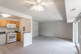 This single-floor unit offers a practical and comfortable layout that flows naturally between its main living spaces. The open-concept living and dining area is generously sized, finished with neutral-toned carpeting and illuminated by a ceiling fan with integrated lighting. A standout feature is the sliding glass door that opens onto a private balcony, framing views of surrounding mature trees and filling the space with natural light. A double closet along one wall provides ample storage within the living area.

The kitchen is efficiently designed with warm honey-toned cabinetry, dark countertops, and white appliances including a gas range, dishwasher, over-the-range microwave, and refrigerator. Tile flooring and a corner sink complete the functional workspace. A half-wall separates the kitchen from the living area, maintaining an open feel while defining the two spaces.

Two carpeted bedrooms offer comfortable retreats, each featuring closet storage. One bedroom includes a standard reach-in closet, while the other benefits from a larger double-door closet. Two bathrooms serve the unit: one full bath with a tub/shower combination, wood-framed vanity, and tile flooring, and a second bathroom with mosaic tile flooring and a single vanity with a framed mirror.