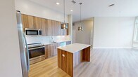 This well-appointed 2-bedroom, 2-bathroom residence at 400 W Swedesford Rd in Berwyn, PA offers a thoughtfully designed single-floor layout with modern finishes throughout. The open-concept kitchen and living area serves as the heart of the home, showcasing warm wood-grain cabinetry extending to the ceiling, sleek white quartz countertops, a subway tile backsplash, and a full suite of stainless steel appliances. A central kitchen island with a matching quartz top and pendant lighting adds both functionality and style. Light hardwood flooring flows through the main living areas, enhancing the bright, airy feel complemented by large windows that invite natural light. The living room offers generous proportions and direct access to outdoor views. Both bedrooms feature plush carpeting and ample natural light, with the primary bedroom including a dedicated walk-in closet fitted with wire shelving systems. The bathrooms are finished with tile flooring, warm wood vanities, and clean white fixtures. Two closets throughout the residence provide excellent storage capacity. The overall aesthetic is clean and contemporary, with a neutral color palette that creates a calm, welcoming ambiance throughout.
