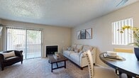 Located at 6155 Palm Ave in San Bernardino, CA, this 2-bedroom, 2-bathroom unit offers a thoughtfully designed single-level layout. The living room is a welcoming focal point, featuring a fireplace, plush carpeting, and a sliding glass door with vertical blinds that opens to a private balcony with outdoor views — filling the space with natural light. A hallway connects the main living area to the rest of the unit, accented with decorative wall art. The dining area sits adjacent to the living room and includes a ceiling fan, adding to the functional open flow. The kitchen is well-equipped with white cabinetry, granite-style countertops, stainless steel appliances including a gas range, microwave, refrigerator, and dishwasher, complemented by wood-look flooring and a tray ceiling with recessed lighting. The primary bedroom offers a comfortable carpeted retreat with a mirrored sliding closet, natural light from a large window, and greenery views. The second bedroom is equally well-lit with vibrant curtains. Both bathrooms feature wood-look flooring; one includes a soaking tub with a granite-top vanity, while the second offers a tub-shower combination with clean finishes throughout.