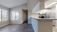 This single-floor residence offers a thoughtfully designed layout with a clean, neutral palette and a variety of flooring finishes that distinguish each living area. The living room serves as the heart of the home, highlighted by a classic fireplace framed by two large windows fitted with horizontal blinds, allowing natural light to fill the space. Wood-look plank flooring runs through the main living and kitchen areas, lending warmth and cohesion to the open floor plan.

The kitchen is well-equipped with stainless steel appliances, including a range with hood ventilation and a full-size refrigerator. Crisp white shaker-style cabinetry provides generous storage, while the light quartz countertops and a stainless steel sink add a polished finish. A peninsula counter with a raised bar connects the kitchen to the adjoining living space.

Multiple bedrooms feature plush carpeting and large windows that invite natural light. One bedroom includes a built-in closet with shelving for added organization, while a ceiling fan in the dining area enhances comfort. The bathroom is neatly appointed with a tub-shower combination, a vanity with quartz countertop, white cabinetry, and wood-look tile flooring. Throughout the space, textured ceilings and clean white trim complete the cohesive and functional design.