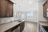 This 1,110 sq ft single-floor apartment at 2015 Wave Crest Drive in Brentwood, NC offers 2 bedrooms and 4 bathrooms with a thoughtfully designed layout. The open living room features hardwood-style flooring, crown molding, a ceiling fan, and large multi-pane windows that fill the space with natural light. A breakfast bar connects the living area to the galley-style kitchen, which is equipped with stainless steel appliances—including a refrigerator, range, microwave, and dishwasher—rich dark wood cabinetry, and granite countertops. The primary bedroom spans 180 sq ft and includes plush carpeting, a ceiling fan, a walk-in closet with wire shelving, and a private en-suite bathroom featuring dark wood vanity and a glass-enclosed shower. The second bedroom also offers carpet flooring, a ceiling fan, and generous windows with outdoor views. Bathrooms throughout include a soaking tub/shower combo with brushed nickel fixtures. The dedicated laundry room houses a full-size washer and dryer with overhead cabinetry. Two closets, three hallways, and consistent finishes across the unit contribute to a clean, functional, and modern living environment.