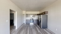 Located at 651 Osigian Blvd in Warner Robins, Georgia, this single-floor 2-bedroom, 2-bathroom unit offers a clean, modern aesthetic with consistent finishes throughout. Light gray wood-style flooring flows seamlessly across all rooms, complemented by neutral walls and crisp white trim that create a bright, cohesive feel.

The kitchen is well-appointed with dark espresso shaker-style cabinetry, granite countertops, and a full suite of stainless steel appliances including a range, microwave, and refrigerator. The layout provides ample cabinet storage and workspace.

Both bedrooms are comfortably sized, with the primary bedroom offering generous dimensions and direct access to a closet. Each bedroom features a ceiling fan, a wall-mounted mini-split unit for individualized climate control, and windows that bring in natural light with views of the surrounding neighborhood. The second bedroom also benefits from dual windows.

The bathrooms are finished with dark wood cabinetry, granite-topped vanities, framed LED mirrors, and wood-style flooring that ties into the rest of the unit. The primary bath includes a soaking tub. A hallway connects the living areas to the bedrooms and closet, keeping the layout functional and efficient. Overall, the unit presents a fresh, move-in-ready interior with modern, consistent design details.