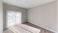 This single-floor residence is designed with a practical, open layout that connects the kitchen and living area seamlessly. The kitchen is outfitted with rich dark-espresso cabinetry, black appliances including a gas range, refrigerator, and built-in microwave, along with light countertops and a double-basin sink. A peninsula with pendant lighting above defines the transition between the kitchen and the carpeted living area, which receives generous natural light through large windows fitted with vertical blinds.

A dedicated laundry area is conveniently accessible directly from the kitchen and accommodates a full-size washer and dryer. The bedrooms are carpeted and bathed in natural light, with neutral-toned walls and ample closet space, including a generously sized walk-in closet fitted with white wire shelving systems on multiple walls for versatile storage. The primary bedroom connects directly to an en-suite bathroom featuring dark cabinetry, a wide white countertop with an undermount sink, and a large mirror with a lit vanity fixture above. A secondary bathroom offers a clean, simple design with a single-basin vanity and matching vanity lighting. Wood-look flooring runs through the kitchen, laundry, and bathroom areas, while plush carpet covers the living and bedroom spaces throughout.
