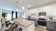 Located at 3050 Millennium Way in Kissimmee, FL, this thoughtfully designed one-bedroom, one-bathroom residence offers a comfortable and modern living experience across a single floor. The open-concept layout seamlessly connects the kitchen and living room, creating a spacious, airy feel throughout.

The kitchen is a standout feature, boasting granite countertops, a large center island with bar seating illuminated by pendant lighting, white upper cabinetry, slate-gray lower cabinets, and a full suite of stainless steel appliances including a refrigerator, range, microwave, and dishwasher. Wood-look flooring flows throughout the main living areas, adding warmth and continuity.

The living room is bright and welcoming, featuring a ceiling fan, large windows dressed with navy curtains, and ample space for relaxing or entertaining. The bedroom offers plush carpeting, natural light from dual windows, and a ceiling fan for year-round comfort, with an adjacent closet providing dedicated storage.

The bathroom includes a granite vanity and a full tub-shower combination with clean white tile surround. A dedicated in-unit laundry room houses a full-size washer and dryer with built-in shelving above, adding exceptional everyday convenience to this well-appointed Kissimmee residence.