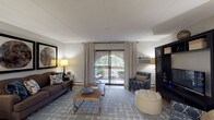 This single-floor residence at 170 Mediterranean Dr in Weymouth, Massachusetts, offers a thoughtfully designed layout with distinct living spaces that flow naturally together. The living room serves as the heart of the home, featuring light hardwood-style flooring, neutral walls, and a large sliding glass door that opens onto a private balcony, filling the space with natural light and outdoor views. A substantial built-in media console anchors one end of the room, complemented by generous seating and a patterned area rug that adds texture and warmth.

Adjacent to the living room, the dining area accommodates a glass-top table beneath an elegant chandelier, with a large decorative mirror and console table enhancing the sense of depth. The kitchen is well-equipped with white cabinetry, gray countertops, stainless steel appliances including a range, microwave, and dishwasher, and light hardwood-style flooring.

The bedrooms feature plush carpeting, soft neutral tones, and windows that invite natural light. Two bathrooms serve the residence—one with a tub-shower combination and a dark wood vanity, the other with a walk-in shower and clean white finishes—both finished with light flooring for a bright, cohesive aesthetic throughout.