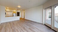 This single-floor unit showcases a clean, contemporary design throughout, with light-toned hardwood-style flooring and crisp white walls creating a bright, cohesive aesthetic. The open-concept living area is spacious and airy, benefiting from natural light admitted through large windows that offer views of the surrounding neighborhood. A wall-mounted HVAC unit ensures climate control directly within the living space.

The kitchen is well-appointed, featuring a two-tone cabinetry scheme that pairs white upper cabinets with warm wood-toned lower cabinets. A full suite of stainless steel appliances includes a refrigerator, electric range, and over-the-range microwave, complemented by a tile backsplash and light countertops. A peninsula provides additional workspace and visual separation from the living area.

The bedrooms are generously sized, each featuring large windows for natural light and built-in closets with shelving systems for organized storage. Two full bathrooms serve the unit; one includes a wood-toned vanity with a white countertop and large mirror, while the other features a grab bar for added accessibility. Both bathrooms include a shower/tub combination with brushed nickel fixtures. A dedicated laundry room houses a full-size Whirlpool front-loading washer and dryer alongside additional shelving.