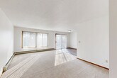This 2-bedroom, 1-bathroom unit at 4901 S Marion Rd in Sioux Falls, SD offers a practical and comfortable single-floor layout. The spacious living room is a standout feature, bathed in natural light streaming through large windows and a sliding glass door fitted with vertical blinds, which also provides outdoor access. A baseboard heating system runs along the perimeter, and neutral carpet flooring adds warmth to the space.

The kitchen is efficiently designed with rich dark-wood cabinetry, light granite-style countertops, wood-look tile flooring, and a full suite of white appliances including a range, over-the-range microwave, dishwasher, and refrigerator. It opens toward the rest of the living area, creating a connected flow throughout the unit.

Both bedrooms feature plush carpeting, closets, and baseboard heating. The primary bedroom is generously sized and well-lit, while the second bedroom includes a window with natural light. Two closets provide ample storage throughout the unit.

The bathroom is clean and functional, featuring a tub/shower combo, a dark-wood vanity with a granite-style countertop, a large mirror, wood-look flooring, and baseboard heating. The entryway transitions seamlessly between the carpeted living space and hard-surface flooring, completing this well-appointed unit.