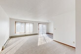 This 2-bedroom, 1-bathroom unit at 4901 S Marion Rd in Sioux Falls, SD offers a practical and comfortable single-floor layout. The spacious living room is a standout feature, bathed in natural light streaming through large windows and a sliding glass door fitted with vertical blinds, which also provides outdoor access. A baseboard heating system runs along the perimeter, and neutral carpet flooring adds warmth to the space.

The kitchen is efficiently designed with rich dark-wood cabinetry, light granite-style countertops, wood-look tile flooring, and a full suite of white appliances including a range, over-the-range microwave, dishwasher, and refrigerator. It opens toward the rest of the living area, creating a connected flow throughout the unit.

Both bedrooms feature plush carpeting, closets, and baseboard heating. The primary bedroom is generously sized and well-lit, while the second bedroom includes a window with natural light. Two closets provide ample storage throughout the unit.

The bathroom is clean and functional, featuring a tub/shower combo, a dark-wood vanity with a granite-style countertop, a large mirror, wood-look flooring, and baseboard heating. The entryway transitions seamlessly between the carpeted living space and hard-surface flooring, completing this well-appointed unit.