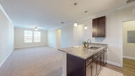 Located at 1124 Crosstown Way in Orlando, Florida, this well-appointed single-story, three-bedroom, two-bathroom home offers a thoughtfully designed layout with comfortable living spaces throughout. The open-concept great room seamlessly connects the kitchen, dining, and living areas, creating a welcoming, cohesive environment. Crown molding and arched architectural details add a refined touch, while a ceiling fan enhances comfort in the living area. Plush carpeting flows through the living and bedroom spaces, complemented by wood-look flooring in the kitchen and bathrooms. The kitchen is a standout feature, showcasing rich dark cabinetry, granite countertops, a peninsula island with a stainless steel sink, pendant lighting, stainless steel appliances—including a refrigerator, range, and microwave—and track lighting overhead. The generously sized primary bedroom includes a walk-in closet with built-in wire shelving. Additional bedrooms offer carpet flooring, natural light from windows with blinds, and their own closets. The bathrooms feature granite-topped vanities, dark wood cabinetry, wood-look tile flooring, and a tub/shower combination with elegant marble-style tile surround. A dedicated laundry room with a full-size washer and dryer completes this functional and attractive home.